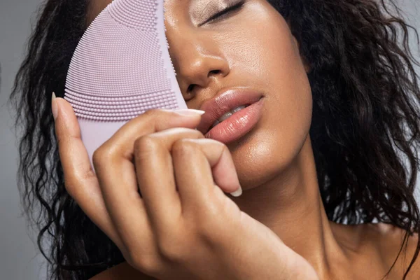 Relaxed Afro American lady keeping silicone brush for face in her hand — Stock Photo, Image
