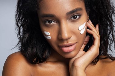 Seksi Afro-Amerikan kadın yüz kremi sürüyor.