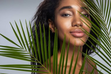 Kameraya poz veren kıvırcık saçlı sakin kadın.