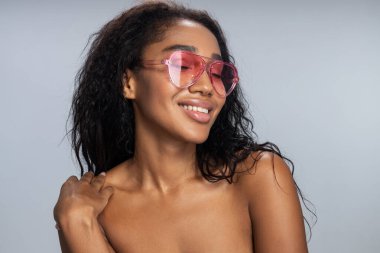 Modern renk gözlüklü mutlu kadın stüdyoda ışık arka planında poz veriyor.