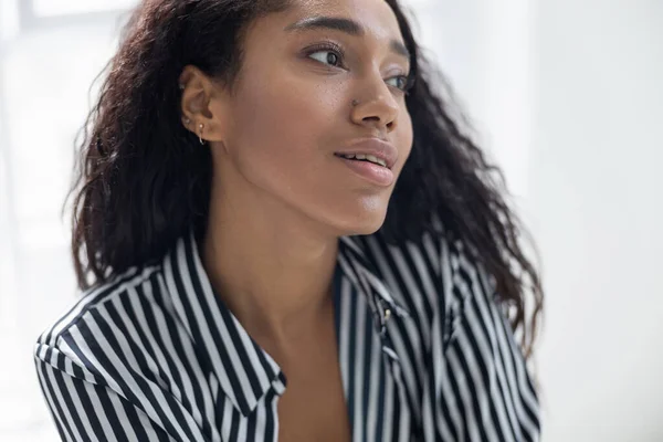 Nette afroamerikanische Dame in gestreiftem Hemd, die sich zu Hause ausruhen kann — Stockfoto