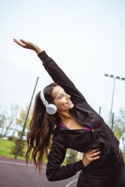 Neşeli genç sporcu kadın vücudunu zevkle esnetiyor.