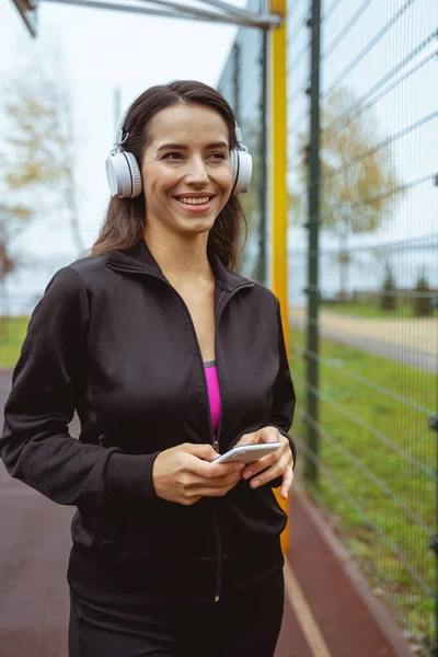 Mujer alegre activa caminando con música en los oídos — Foto de Stock