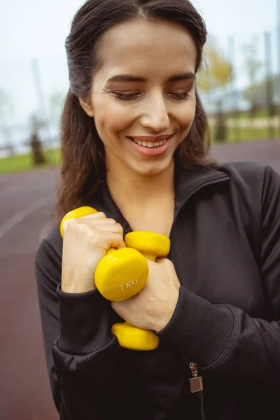 Retrato de una chica amable que sostiene pesas — Foto de Stock