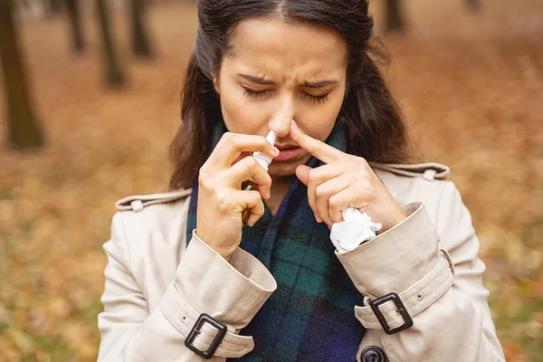 Nemocná mladá bruneta žena klesající její nos — Stock fotografie