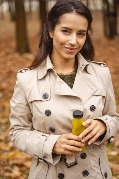 Positiva mujer joven encantada sosteniendo la botella con jugo —  Fotos de Stock