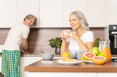 Neşeli orta yaşlı koca karısına bakıyor.