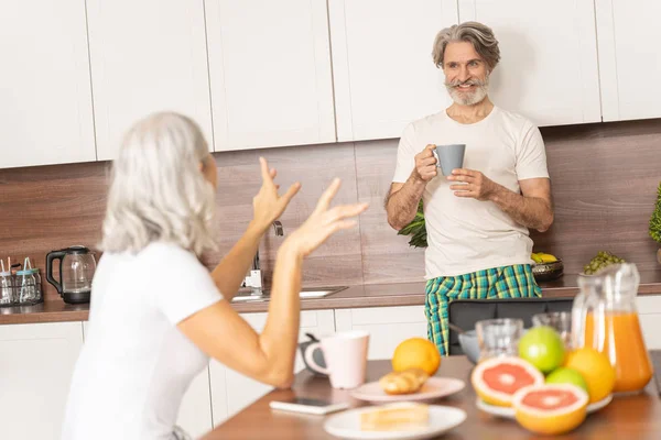 Kvinnan pratar med sin man i köket — Stockfoto