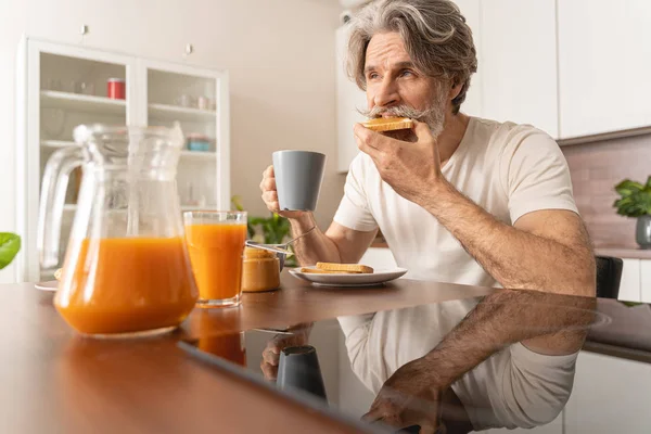 Hombre serio comiendo su tostada de mantequilla de maní — Foto de Stock