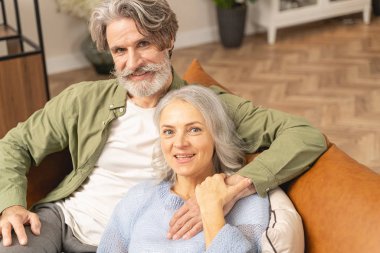 Loving middle-aged man embracing his pleased wife clipart