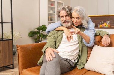 Bayan, memnun kocasına arkadan sarılıyor.