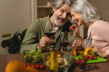 Neşeli bir adam ve karısı birlikte yemek pişiriyor.