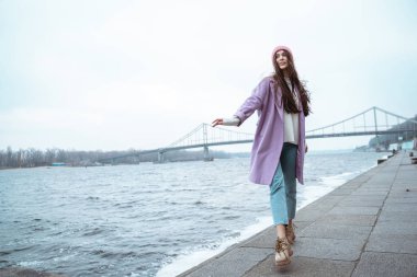 Neşeli esmer kız kıyıda tek başına yürüyor.