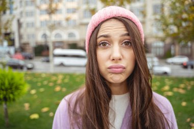 Genç esmer kadın doğrudan kameraya bakıyor.