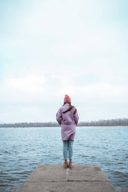 Sınırda duran düşünceli, uzun saçlı kadın.