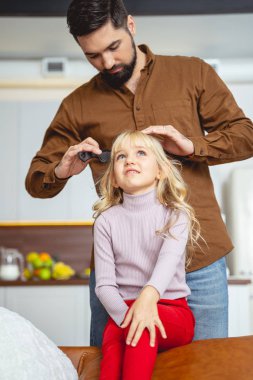 Sevgi dolu baba, kızının saçını tarıyor.
