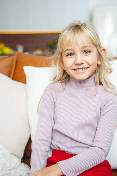 Adorable niña sentada en el sofá en casa —  Fotos de Stock