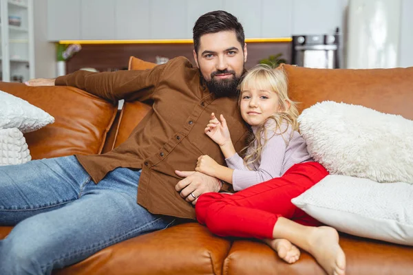 Entzückendes kleines Mädchen sitzt mit ihrem Vater auf der Couch — Stockfoto