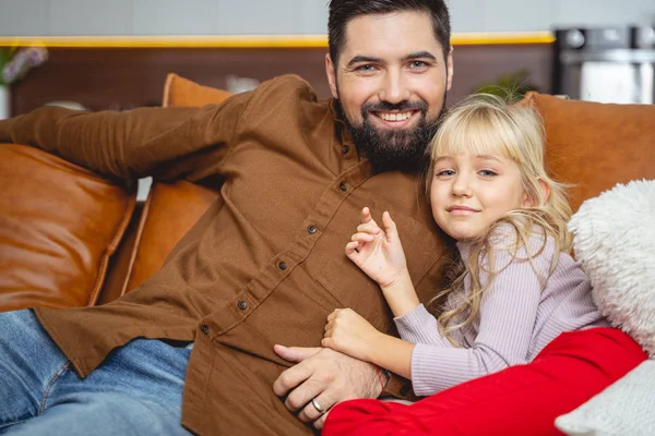 Veselý muž sedí na gauči se svou roztomilou dcerou — Stock fotografie