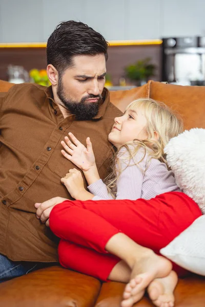 Roztomilá holčička a její otec sedí na gauči — Stock fotografie