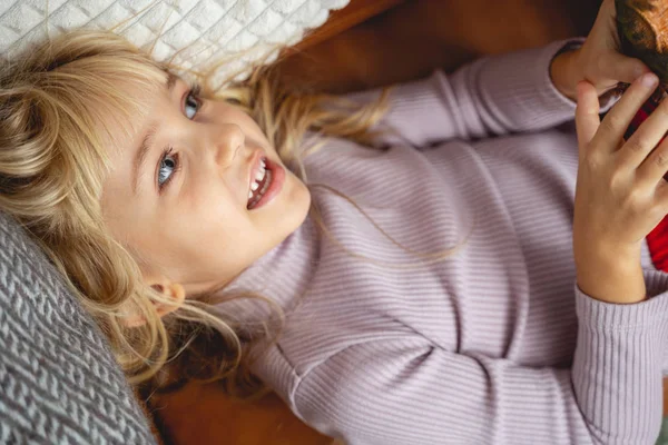 Cute little girl leżące na kanapie w domu — Zdjęcie stockowe