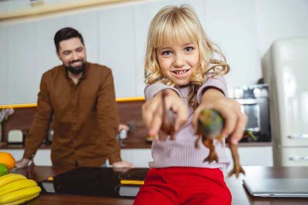 Adorabile bambina che tiene due dinosauri giocattolo — Foto Stock