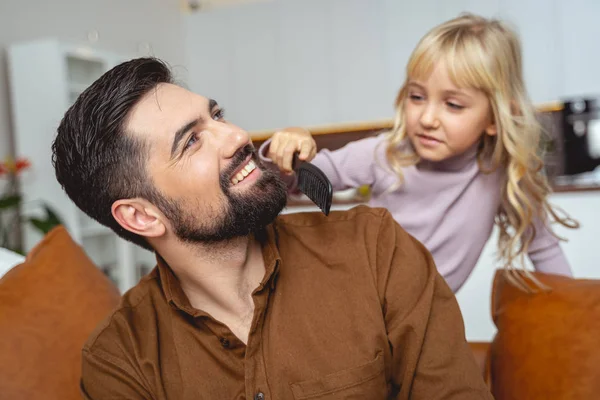 Adorable petite fille brossant la barbe de son père souriant — Photo