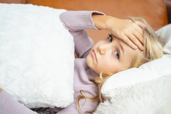 Niña enferma acostada en el sofá y con dolor de cabeza — Foto de Stock