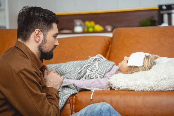 Gondoskodó apa ül a beteg lánya mellett. — Stock Fotó