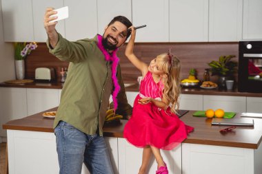 Mutlu baba ve kız evde selfie çekiyorlar.