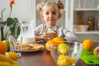 Evdeki mutfak masasında oturan sevimli küçük kız.