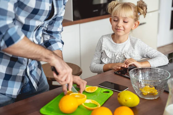Sonriente niña viendo cómo su padre cortaba naranja —  Fotos de Stock