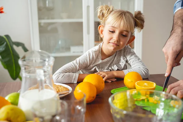 Niedliches kleines Mädchen beobachtet, wie ihr Vater Orange schneidet — Stockfoto