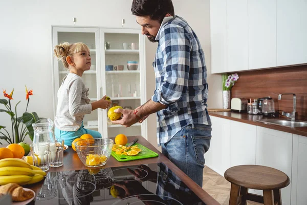 Söt liten flicka tittar på hur pappa matlagning och prata på mobiltelefon — Stockfoto