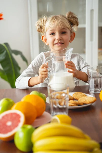 Joyful little girl sitting at the kitchen table at home — Stock Photo, Image