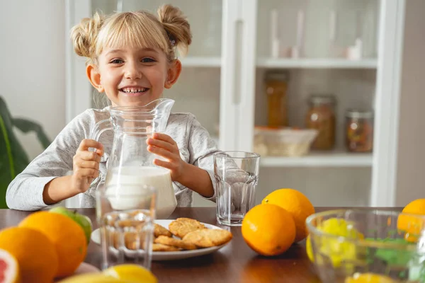 Fröhliches kleines Mädchen mit einem Krug Milch — Stockfoto