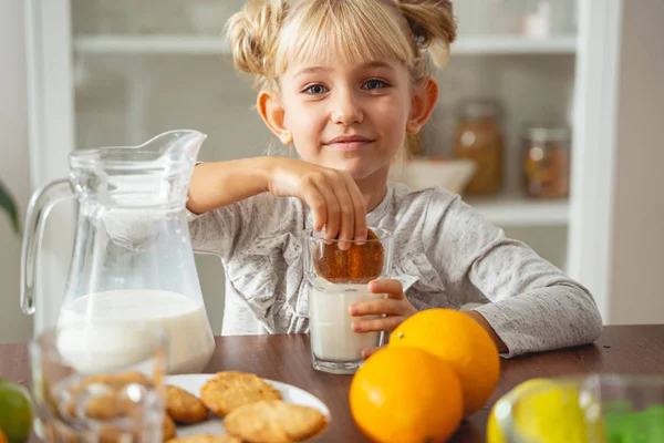 Cute little girl maczania ciasteczka w mleku — Zdjęcie stockowe