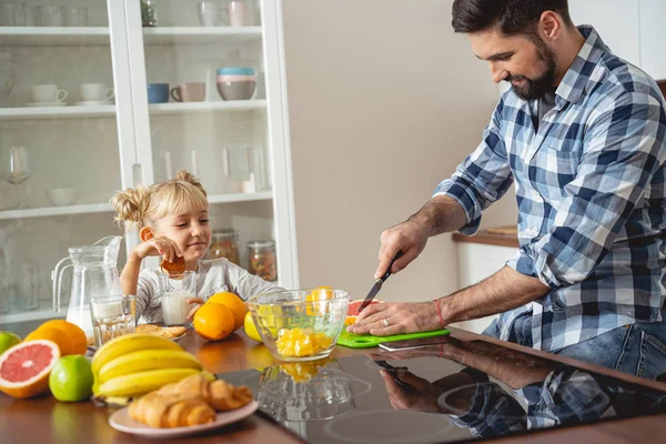 Lächelndes kleines Mädchen beobachtet, wie Vater Grapefruit schneidet — Stockfoto