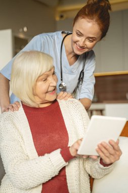 Positive delighted senior woman pointing at her tablet