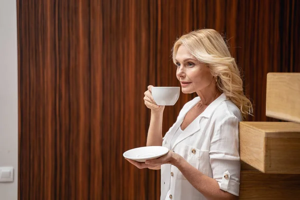 Красивая современная безмятежная женщина пьет кофе в помещении — стоковое фото