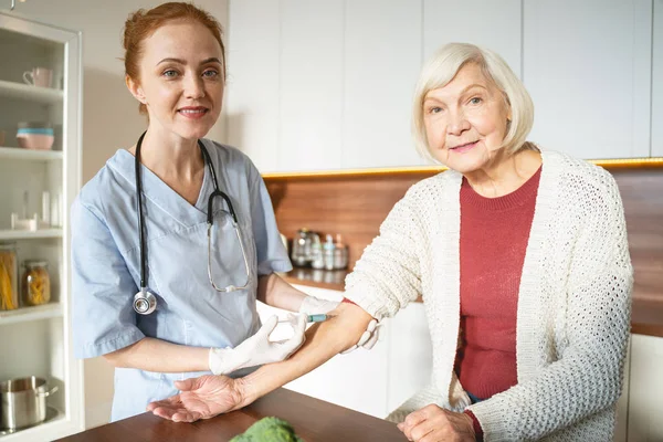 Delighted medical worker standing near her patient — Stock Photo, Image