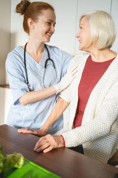 Веселая медицинская работница консультирует своего взрослого гостя — стоковое фото