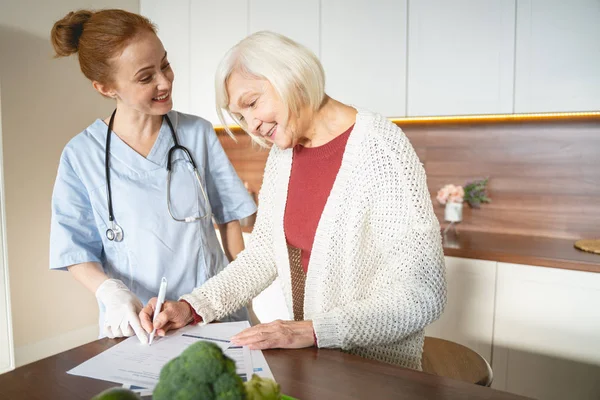 Tevreden volwassen vrouw zetten haar teken op documenten — Stockfoto