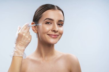 Çekici beyaz kız, arka plandaki aydınlığa karşı güzellik prosedürlerine hazır.