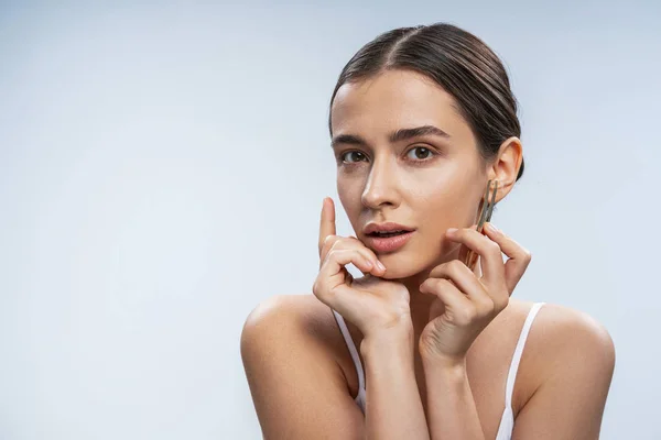 Charming tender girl using tweezers against light background — 스톡 사진