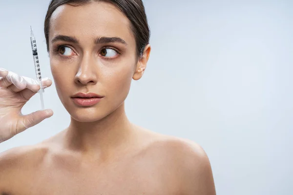 Scared girl is ready for beauty procedures against light background — Stock Photo, Image