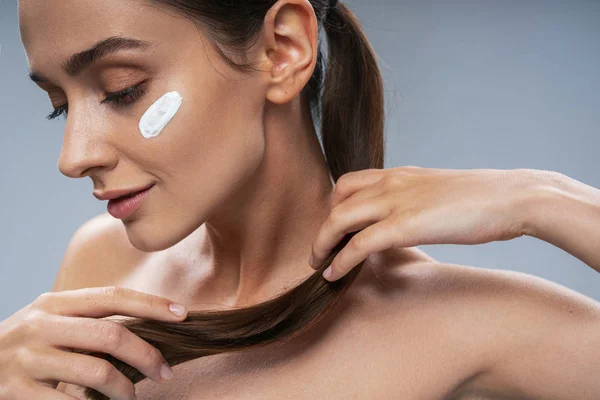 Muchacha atractiva cuidando de la piel facial sobre fondo gris — Foto de Stock