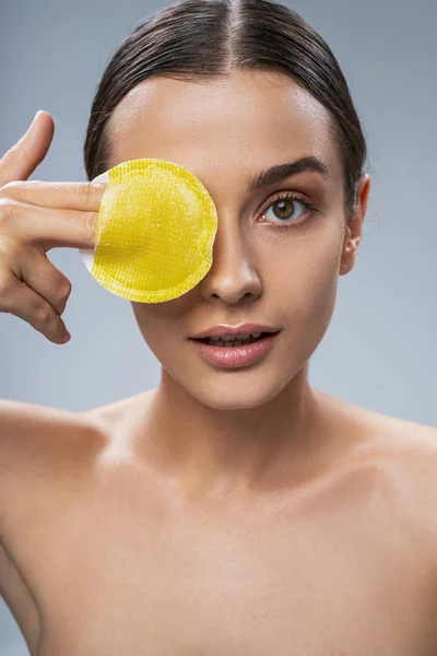 Beautiful girl cleansing her face against grey background — Stock Photo, Image