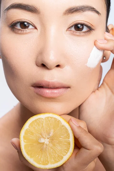 Mujer joven calma aplicando crema en la piel facial — Foto de Stock