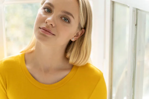 Молодая красивая девушка в желтом свитере позирует перед камерой дома — стоковое фото